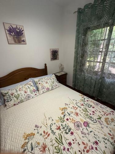 a bedroom with a bed with a floral bedspread and a window at Tijarafe 2 in Tijarafe