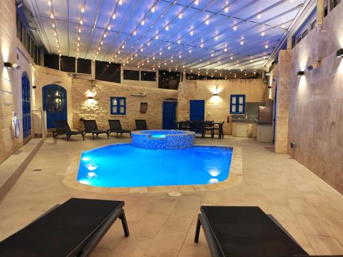 a pool in the middle of a room with lights at Margerita Farmhouse in Qrendi
