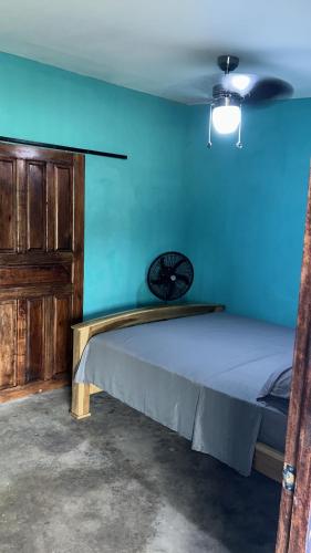 a bed in a room with a blue wall at Habitaciones Lala in Las Peñitas