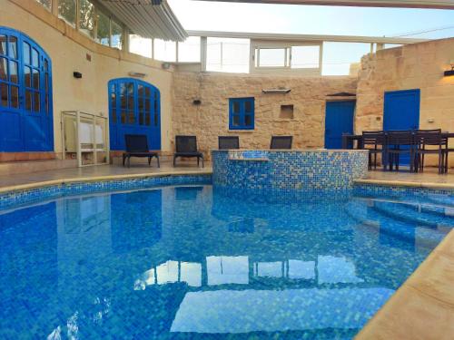 a swimming pool with blue water in a building at Margerita Farmhouse in Qrendi