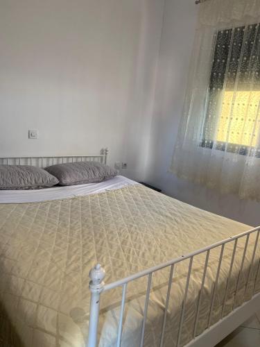 a bed in a white bedroom with a window at Golem Central Stay in Golem