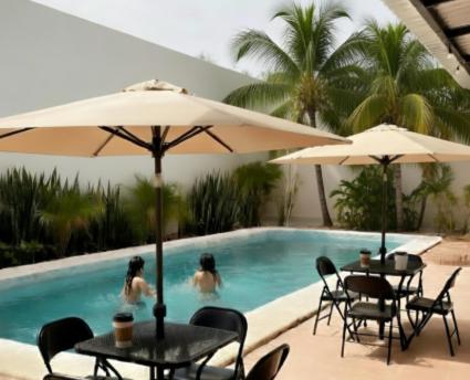 two people in a swimming pool with tables and umbrellas at Estudios Bacalar in Bacalar