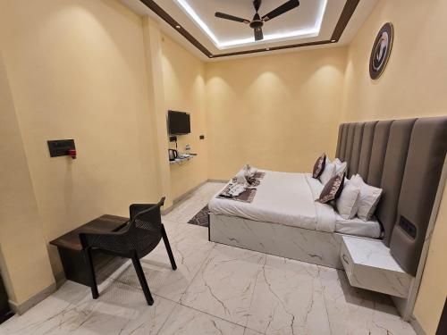 a bedroom with a bed and a chair and a ceiling fan at prabh aasra in Ayodhya