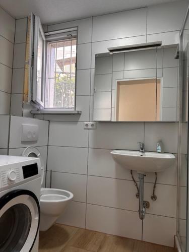 a bathroom with a sink and a toilet and a mirror at Ferienwohnung Trinh in Überlingen