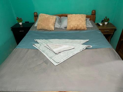 a bed with blue sheets and pillows on it at Casa Tamarindo in Las Peñitas