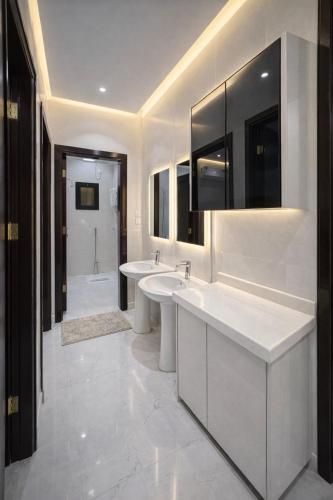 a white bathroom with two sinks and a tub at الشقق الفاخرة luxury aparments in Medina