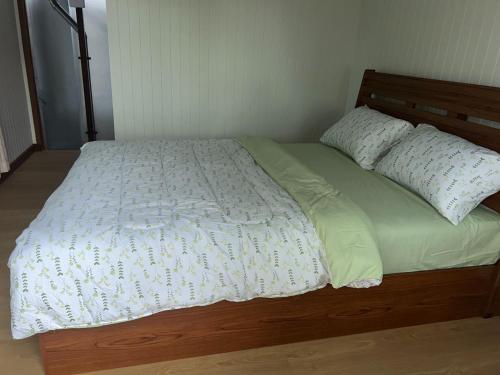 a bed with a wooden headboard and two pillows on it at Homni Living Home in Ban Kohong