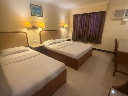 a hotel room with two beds and a window at W Express Hotel in Cebu City