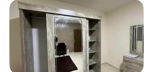 a bathroom with a mirror and a chair in a room at Local apartment in Irbid