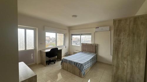a bedroom with a bed and a desk and windows at Local apartment in Irbid