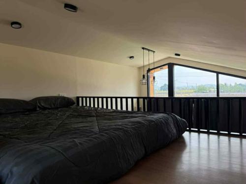 a large bed in a room with a large window at Baan Noah บ้านโนอาห์ in Lop Buri