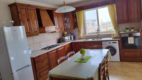 a kitchen with a table and a white refrigerator at Joseph 2, Charming Retreat with park views and close to the airport in Siġġiewi