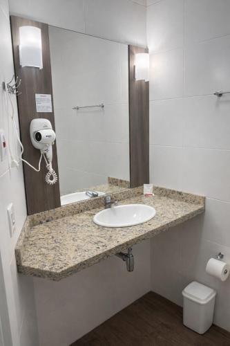 a bathroom with a sink and a mirror at DE STEFANI HOTEL in Portão