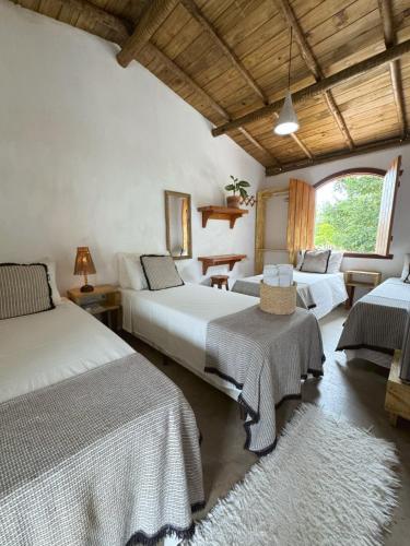 a bedroom with three beds and a large window at Pousada Dendê Caraiva in Caraíva