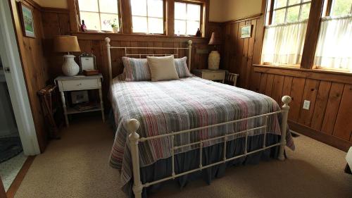 a bedroom with a bed in a room with windows at Cutest Cottage On Central in Cape May Point