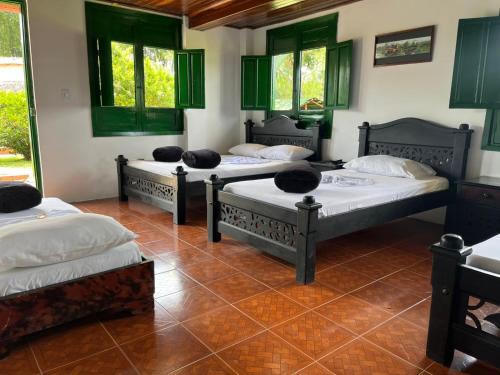 three beds in a room with green windows at Finca Hotel el Rocio in Circasia