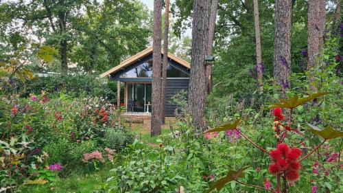 a cabin in the woods with flowers and trees at B&B De Vretberg in Enschede