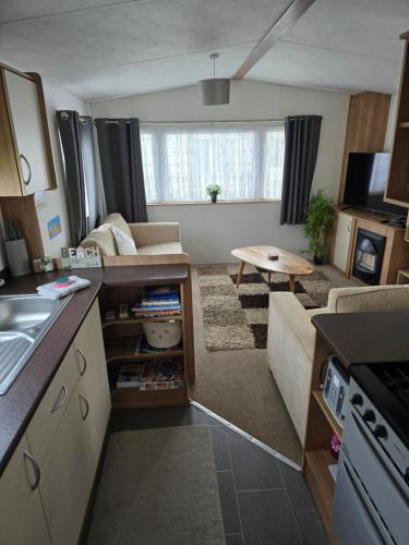 a small kitchen and living room with a couch at B17 Sunnymede Caravan Park, Fantasy Island, Ingoldmells in Ingoldmells