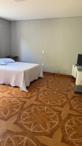 a bedroom with a bed and a wooden floor at Chalés ninhos do cerrado in Cavalcante