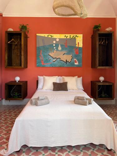 a large white bed in a room with orange walls at allacasett in Favignana