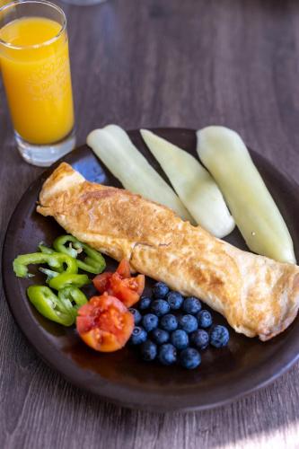 a black plate of food with bread and fruit and a glass of orange juice at Sion Residence in Debrecen