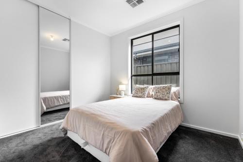 ein Schlafzimmer mit einem Bett und einem großen Fenster in der Unterkunft Stylish Luxury 4BR - Close to Wineries & City in Munno para Downs