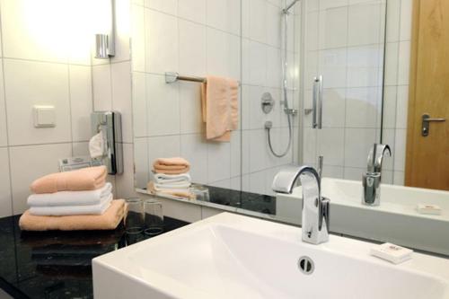 a bathroom with a sink and a mirror and towels at Greifensteiner Hof in Würzburg