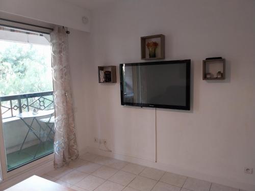 a flat screen tv on a white wall with a window at Menton 1 in Menton