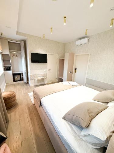 a bedroom with a large white bed and a television at River Stone in Pavlodar
