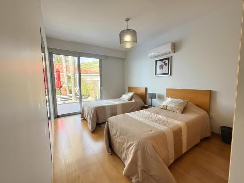 a bedroom with two beds and a sliding glass door at Blue Villa in Arco da Calheta