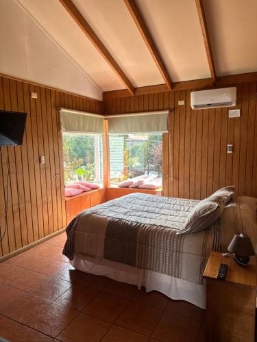 a bedroom with a bed and a large window at Cabañas Bosque Sur in Puerto Varas