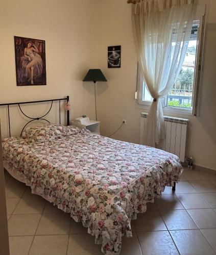 a bedroom with a bed with a floral bedspread and a window at Casa Kelly Chios in Chios