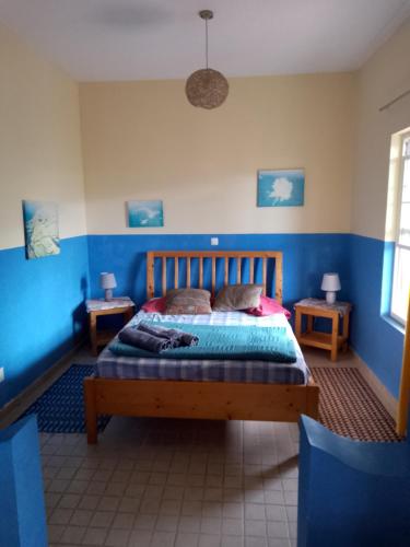 a bedroom with a wooden bed with blue walls at Djabraba's space in Garça