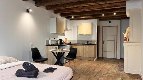 a bedroom with a bed and chairs and a kitchen at Le Chêne Doré in Bellac