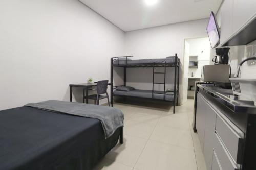 a bedroom with a bed and a desk with a sink at Studio IV Jundiaí - Com Ar Condicionado in Jundiaí