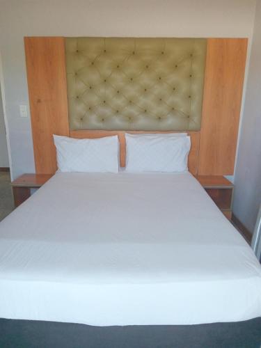 a large white bed with a wooden head board at Star Legend lodge in Parow