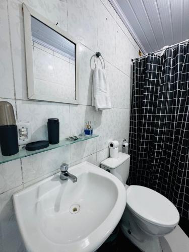a white bathroom with a sink and a toilet at Casa de praia em Itacuruçá in Mangaratiba