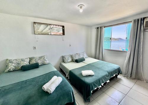 two beds in a room with a view of the ocean at Casa de praia em Itacuruçá in Mangaratiba