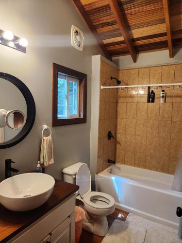 a bathroom with a sink and a toilet and a tub at Cozy Yellow Cottage in Spanish Lookout