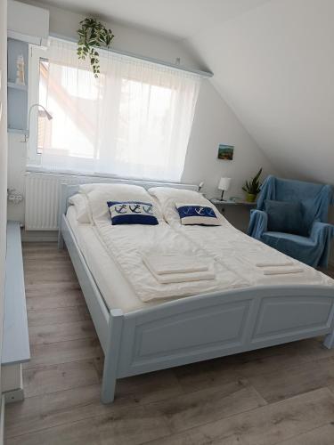 a bedroom with a white bed and a blue chair at Nyárfa Vendégház in Balatonmáriafürdő