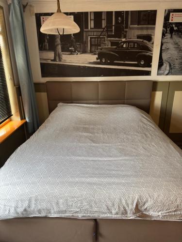 a bed in a room with a picture of a car at Slotje in Egmond aan den Hoef