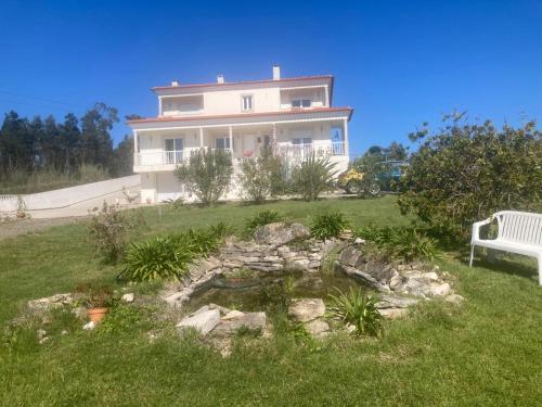 a house with a pond in the yard with a bench at Casa da Alegria Boutique Guest Suite in Caldas da Rainha