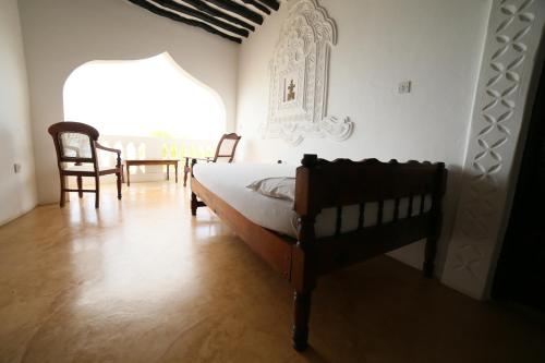 a bedroom with a bed and a table and chairs at Stopover Guest House and Restaurant in Lamu