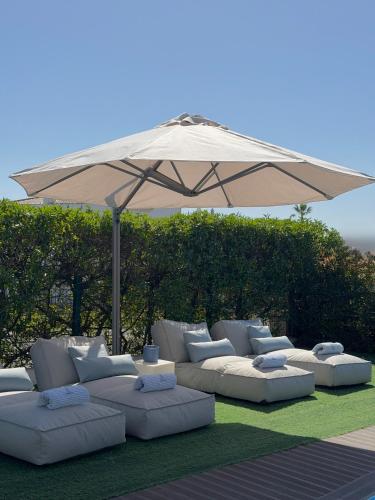 a group of white couches sitting under an umbrella at Villa Amêndoa in Loulé