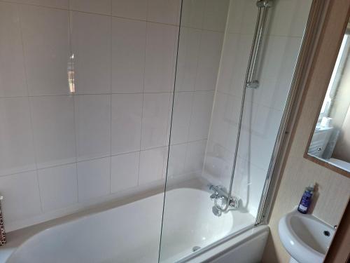 a bathroom with a shower and a tub and a sink at Sunningdale comfy suite in Tattershall