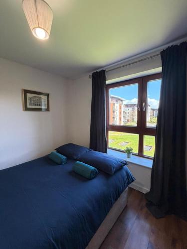 a bedroom with a blue bed with a large window at Superb 3-Bed Residence Airport in Dublin
