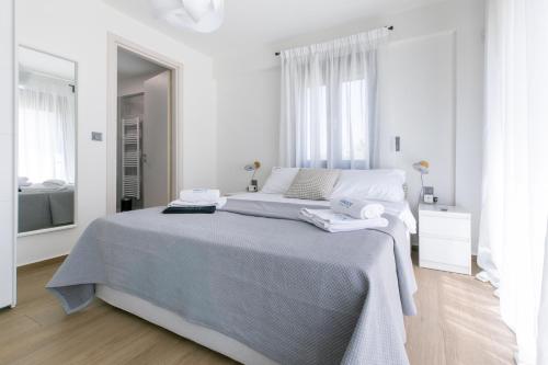 a white bedroom with a large bed and a mirror at Breeze Concept Villa in Drosia