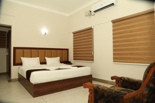 a bedroom with a bed and a chair at Kalathil Kshetra Inn in Guruvāyūr