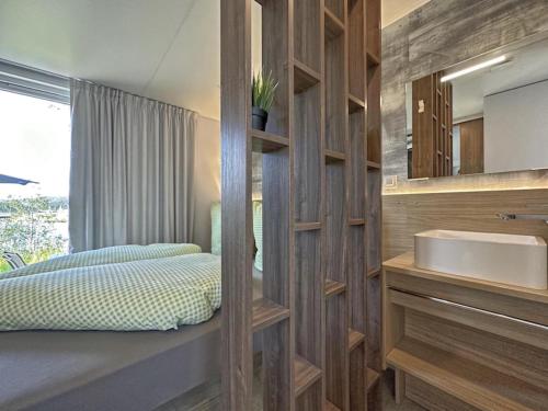 a bathroom with a sink and a bed and a mirror at Feriendorf Seeblick - Tiny Chalet Nr 9 in Neunburg vorm Wald