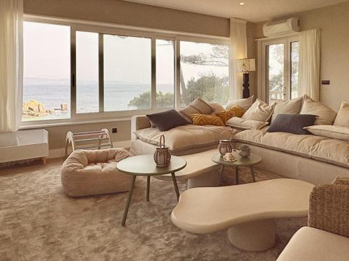 a living room with a couch and tables and windows at Beachfront Luxury Villa in O Grove